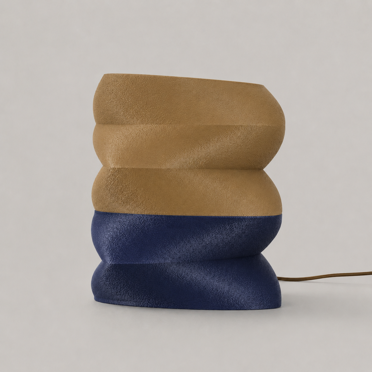 Zaha table lamp unlit, showing the stacked form and the matte grain where amber meets navy